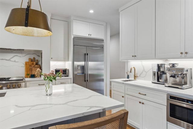 9736 Chiswell Rd, Dallas, TX 75238 - kitchen featuring recessed lighting, a sink, built in appliances, light stone counters, and white cabinetry