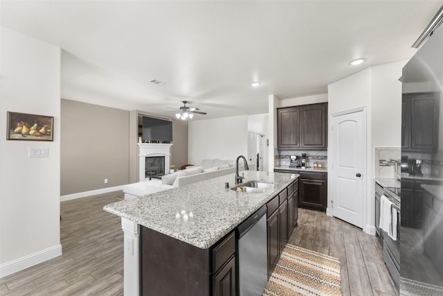 kitchen with a kitchen island with sink, appliances with stainless steel finishes, sink, and hardwood / wood-style flooring