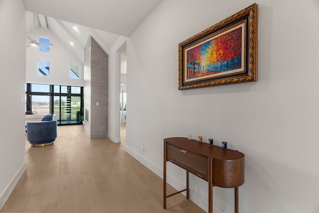 hall with light hardwood / wood-style floors, french doors, and high vaulted ceiling