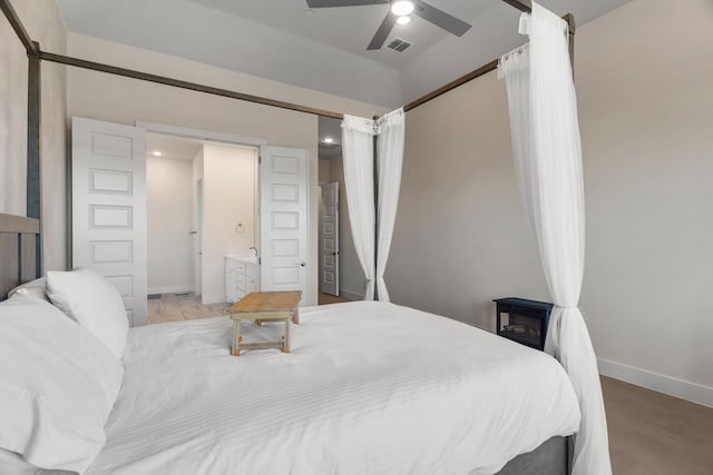 bedroom with ceiling fan, connected bathroom, and light hardwood / wood-style flooring