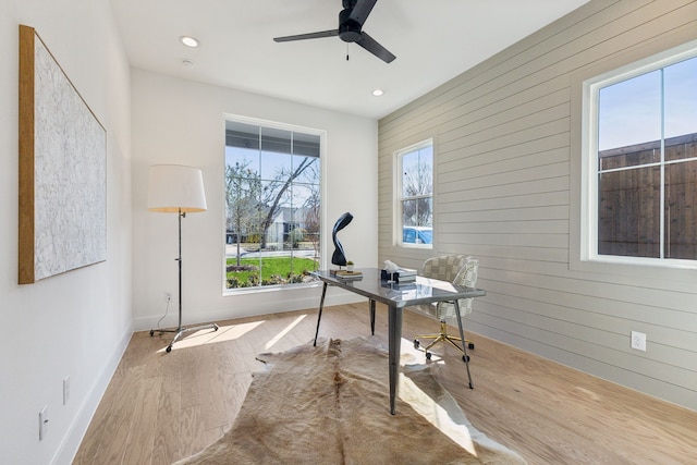 unfurnished office with ceiling fan, wooden walls, and light hardwood / wood-style flooring