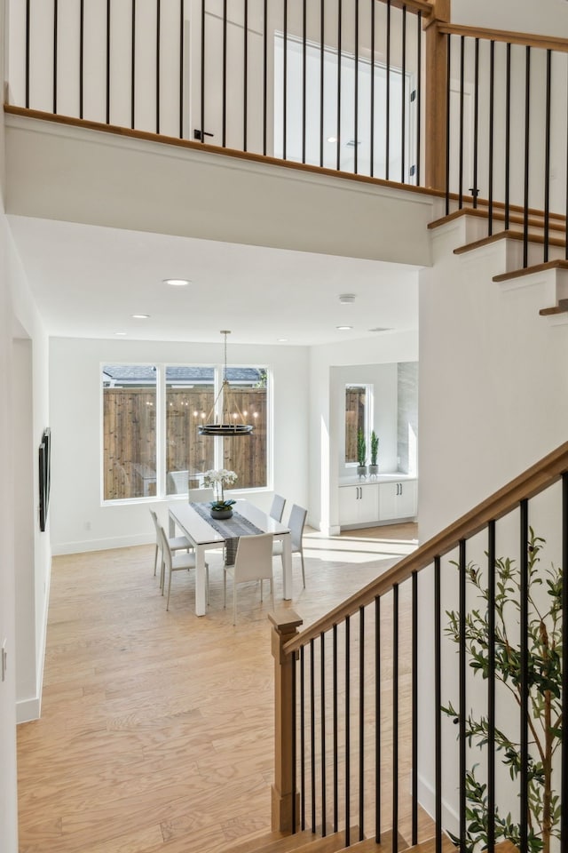 stairs with hardwood / wood-style flooring, a towering ceiling, and a chandelier