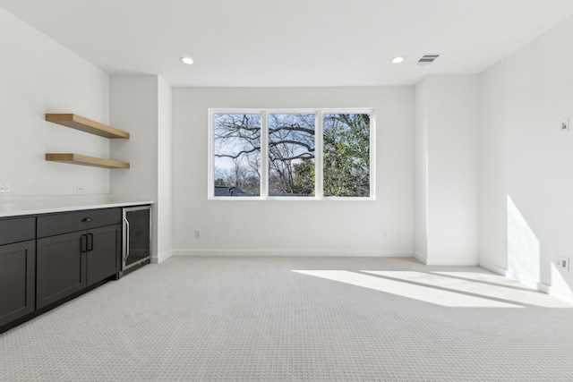 unfurnished living room featuring light colored carpet and beverage cooler