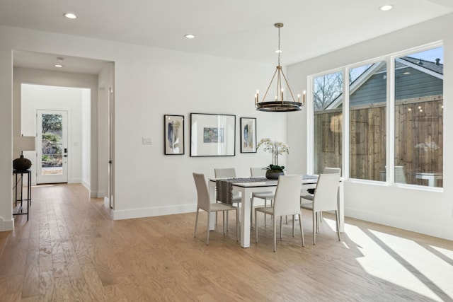 dining room with a healthy amount of sunlight, an inviting chandelier, and light wood-type flooring