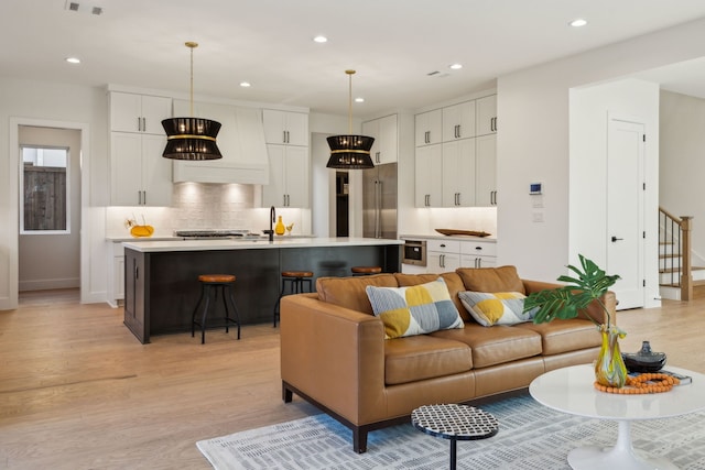 kitchen featuring sink, white cabinetry, a tiled fireplace, and hanging light fixtures