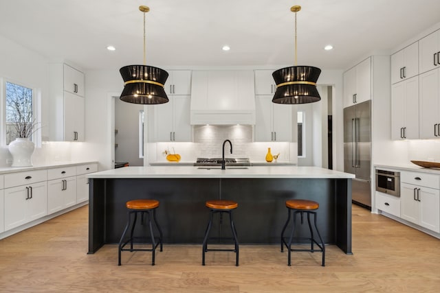 kitchen featuring pendant lighting, a kitchen bar, built in fridge, and a center island with sink