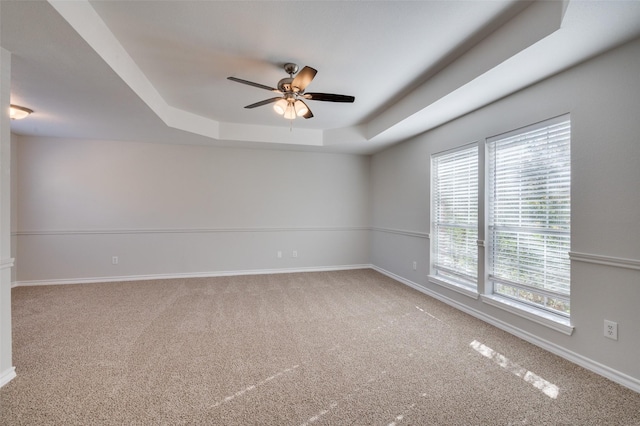 unfurnished room with ceiling fan, carpet flooring, and a tray ceiling