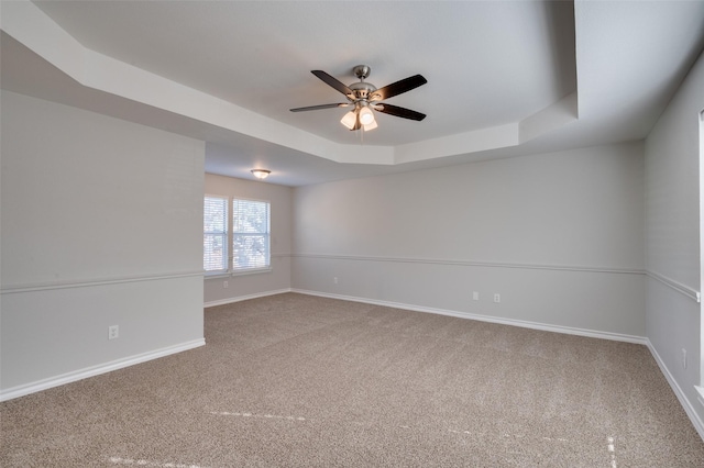 unfurnished room featuring ceiling fan, a raised ceiling, and carpet floors