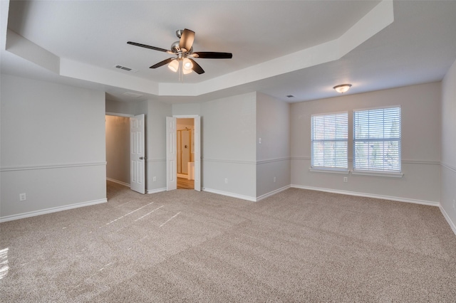 carpeted empty room with a raised ceiling and ceiling fan