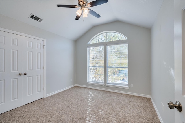 unfurnished bedroom with ceiling fan, light colored carpet, a closet, and lofted ceiling