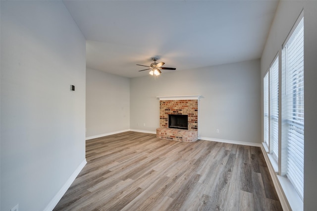 unfurnished living room featuring a brick fireplace, light hardwood / wood-style flooring, and ceiling fan