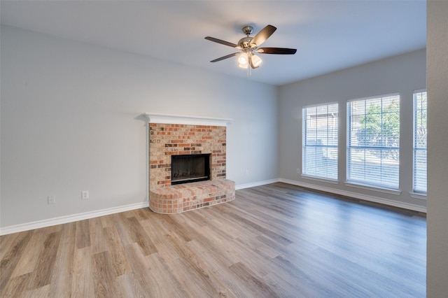 unfurnished living room with ceiling fan, light hardwood / wood-style flooring, and a brick fireplace