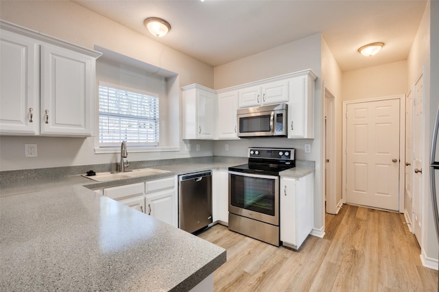 kitchen with white cabinets, appliances with stainless steel finishes, sink, and light hardwood / wood-style flooring