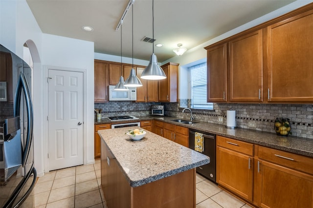 kitchen with pendant lighting, dishwasher, a kitchen island, sink, and refrigerator