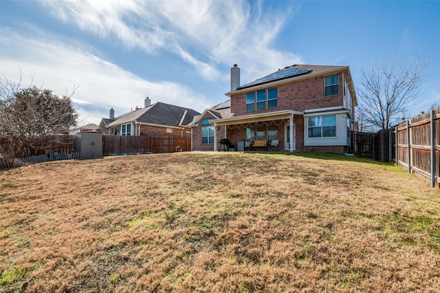 rear view of house featuring a storage shed, a yard, and solar panels