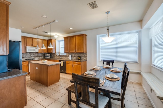 kitchen with a healthy amount of sunlight, a center island, hanging light fixtures, and black appliances