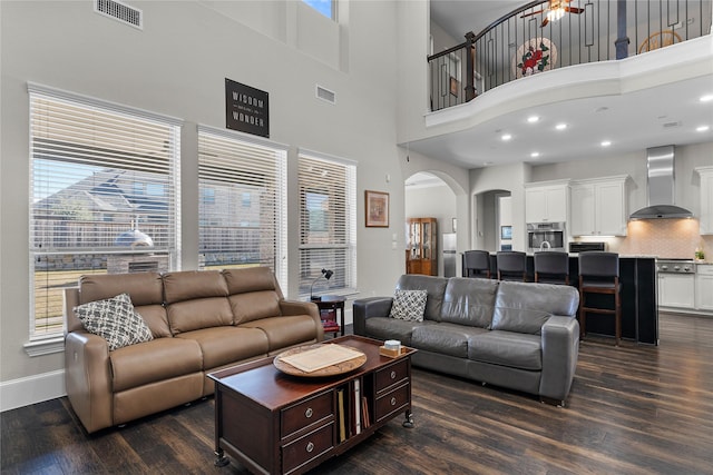 living room featuring arched walkways, a wealth of natural light, and visible vents