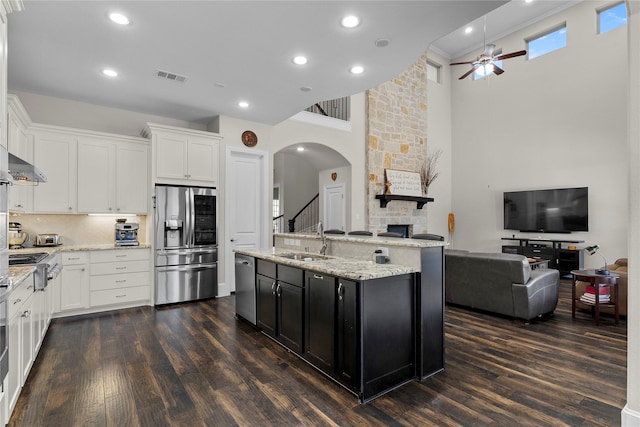 kitchen featuring visible vents, appliances with stainless steel finishes, open floor plan, dark cabinetry, and a sink