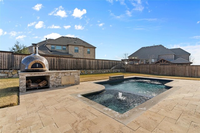 view of pool with pool water feature, an outdoor fireplace, and a patio