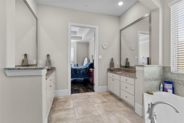 bathroom featuring baseboards, tile patterned floors, ensuite bathroom, a garden tub, and vanity