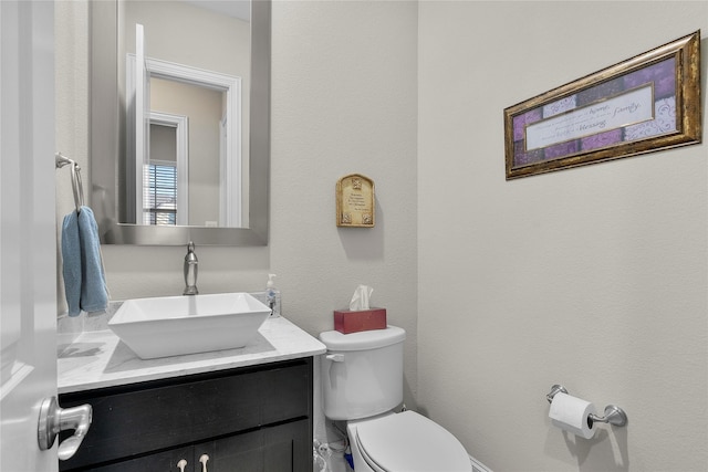 bathroom featuring toilet, a textured wall, and vanity