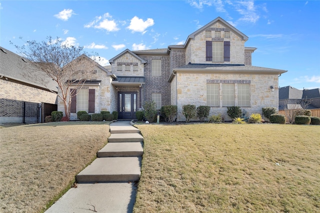 french country home featuring stone siding, fence, a front lawn, and french doors