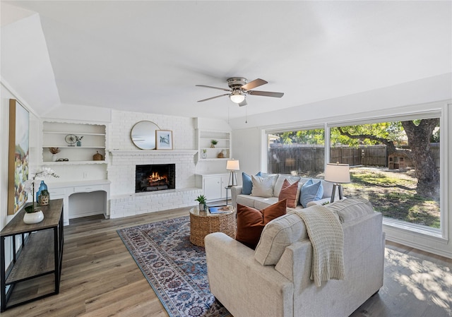 living room with a brick fireplace, plenty of natural light, and built in shelves