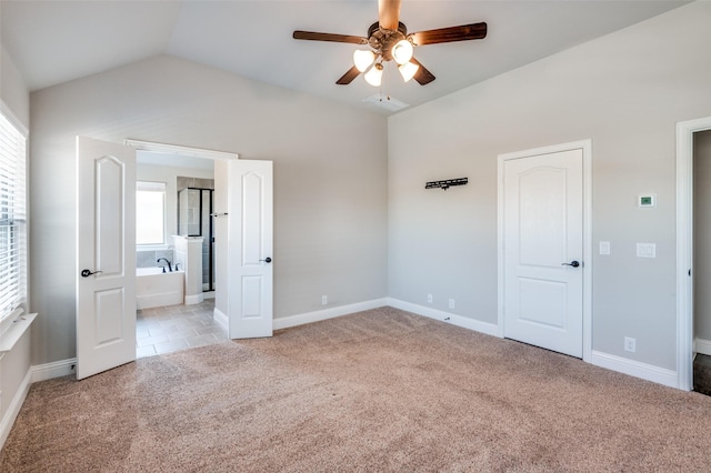 unfurnished bedroom with vaulted ceiling, light colored carpet, ceiling fan, and ensuite bathroom