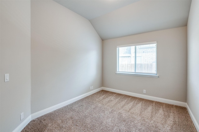 carpeted spare room with vaulted ceiling