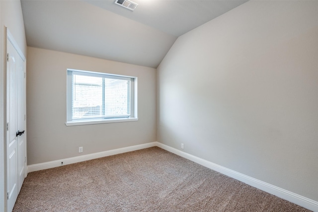 empty room featuring lofted ceiling and carpet flooring