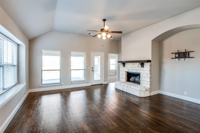 unfurnished living room featuring vaulted ceiling, a stone fireplace, dark hardwood / wood-style floors, and ceiling fan