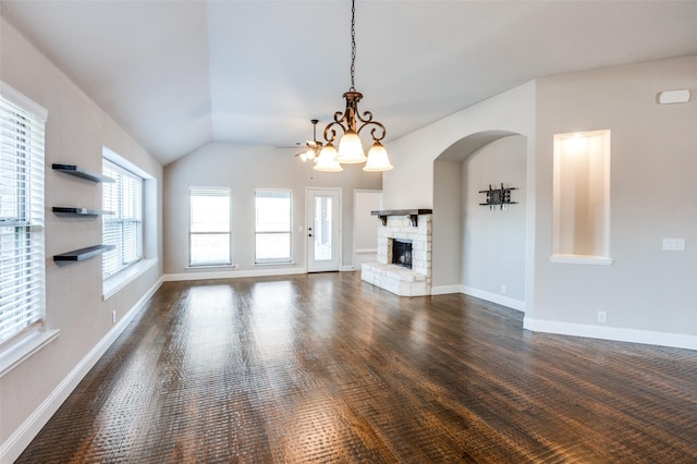 unfurnished living room featuring a stone fireplace, lofted ceiling, and a chandelier