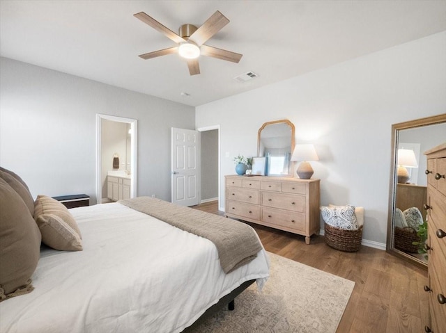 bedroom with ceiling fan, ensuite bathroom, and wood-type flooring