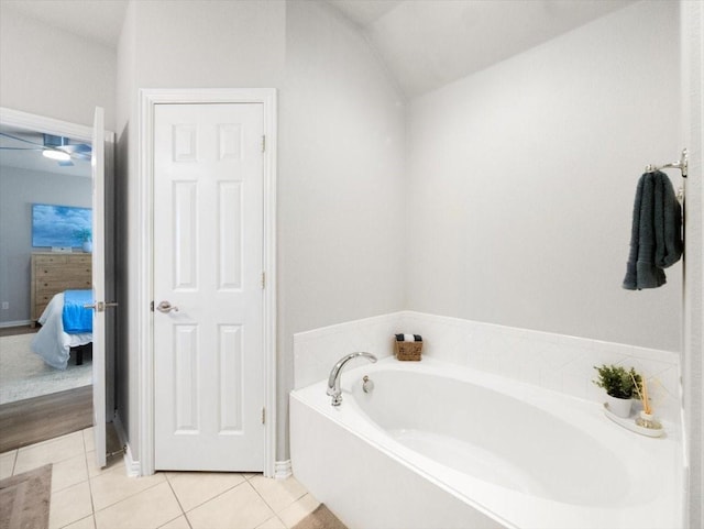 bathroom with vaulted ceiling, a tub to relax in, and tile patterned floors