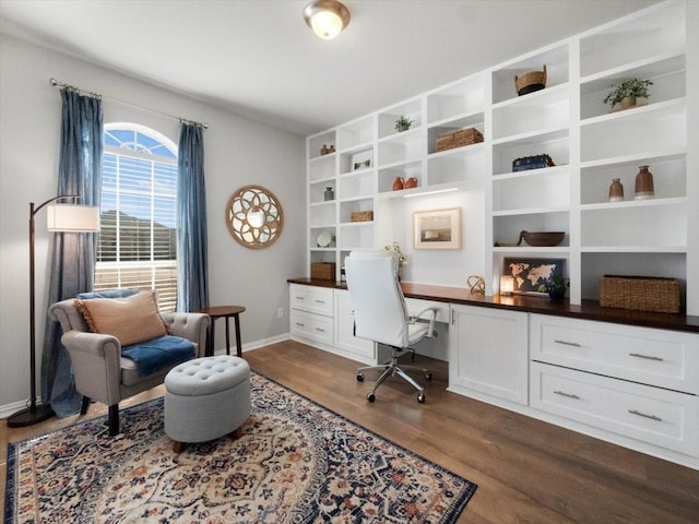 office with built in desk and dark wood-type flooring