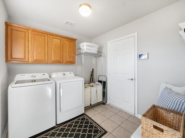 laundry room with washing machine and dryer, cabinets, and light tile patterned floors