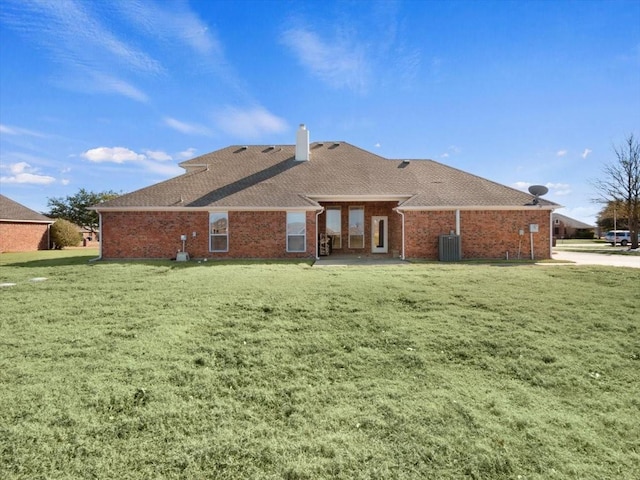 rear view of property with central AC unit and a yard