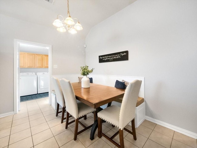 tiled dining space with a notable chandelier, lofted ceiling, and washing machine and dryer