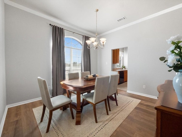 dining space featuring dark hardwood / wood-style flooring, an inviting chandelier, and ornamental molding