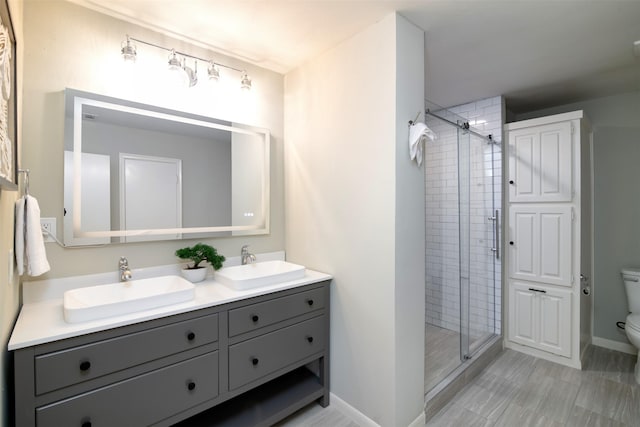 bathroom featuring toilet, a shower with shower door, and vanity