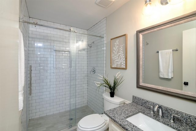 bathroom with vanity, toilet, and a shower with door