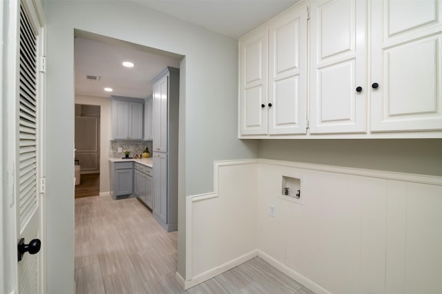 washroom featuring light hardwood / wood-style floors, cabinets, and hookup for a washing machine