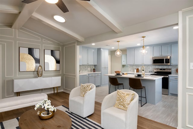 living room featuring ceiling fan, vaulted ceiling with beams, and light hardwood / wood-style floors