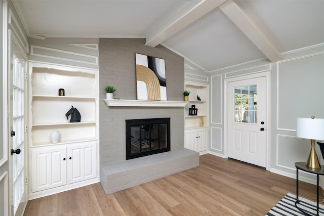 foyer featuring ornamental molding, light hardwood / wood-style floors, a fireplace, and lofted ceiling with beams