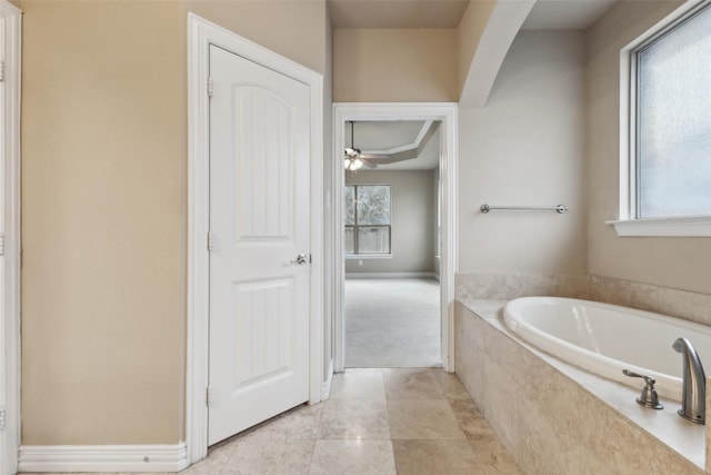 bathroom with tiled bath and ceiling fan