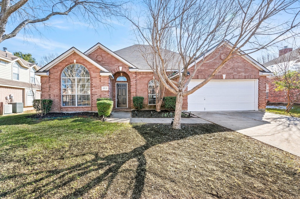 view of front property featuring a front lawn, cooling unit, and a garage