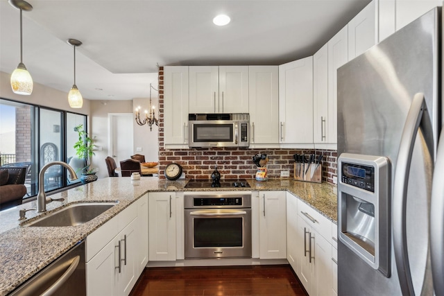 kitchen featuring appliances with stainless steel finishes, decorative light fixtures, stone countertops, white cabinets, and sink