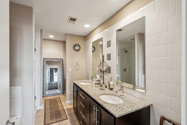 bathroom featuring a shower with door, vanity, tile walls, and tile patterned floors