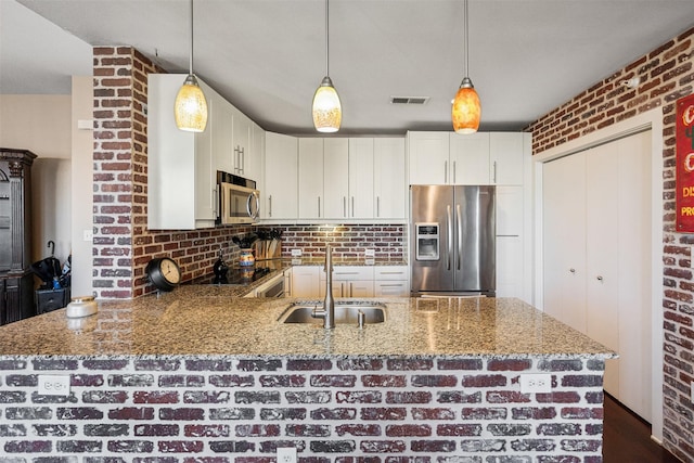 kitchen with light stone countertops, white cabinets, appliances with stainless steel finishes, and sink