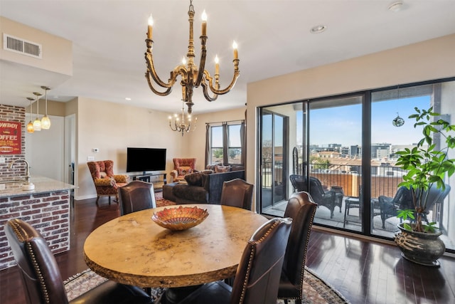 dining area with dark wood-type flooring and a notable chandelier